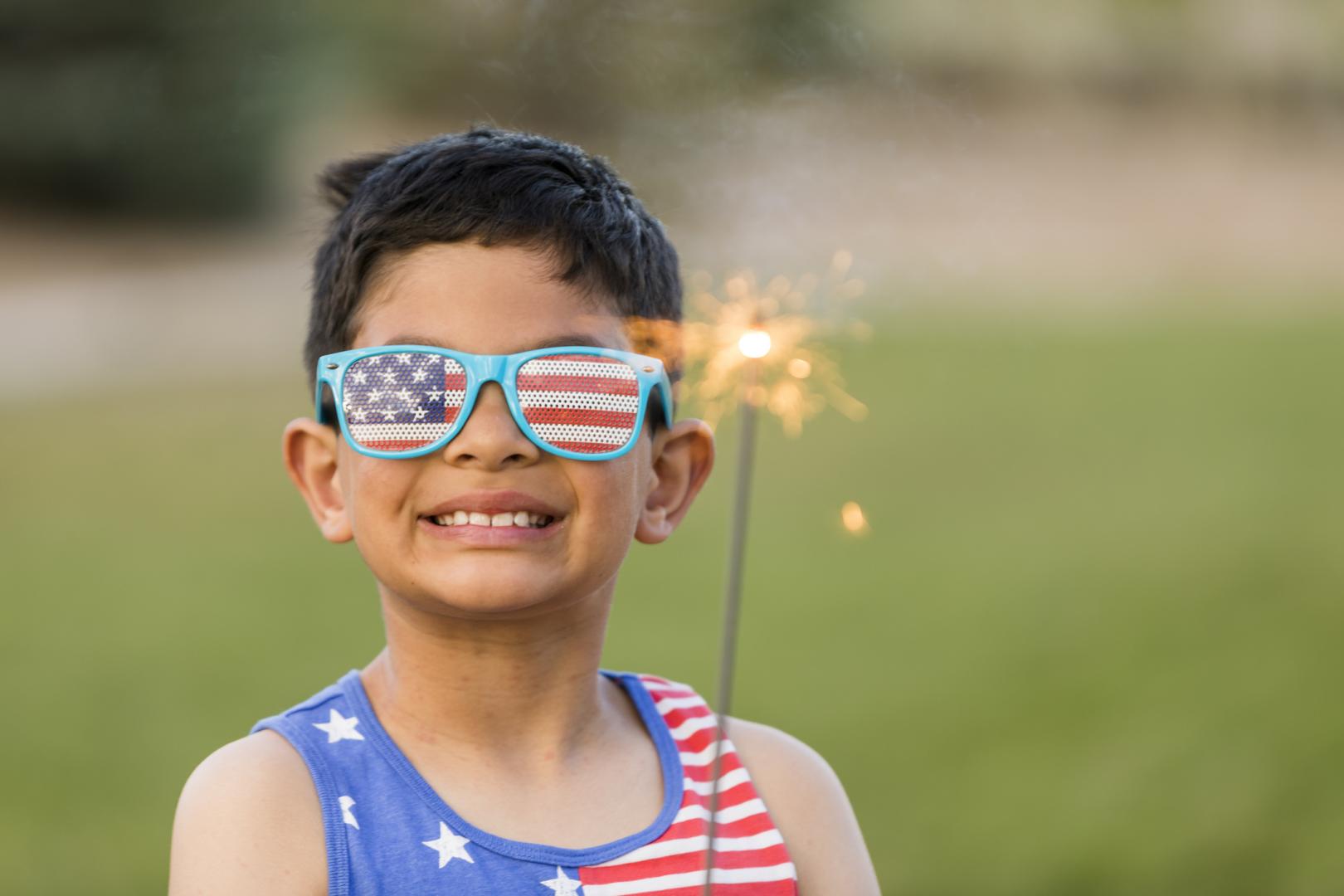 Child with sparkler and USA glasses