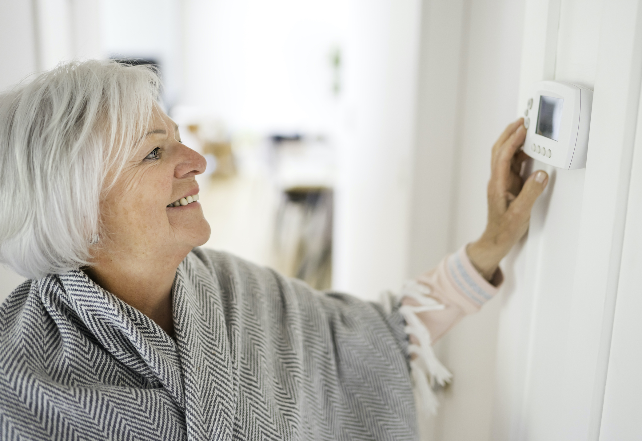 A Senior woman adjusting her thermostat at home