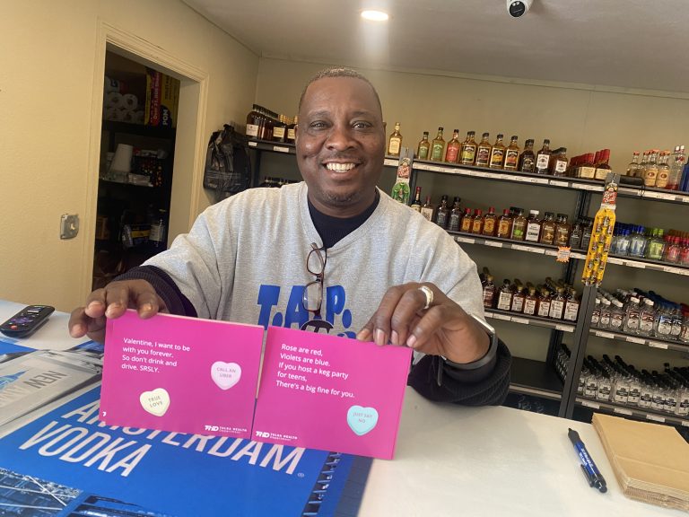 Man holds up valentine cards at liquor store that promote safe messaging