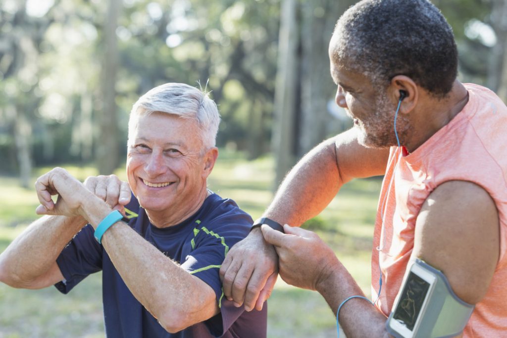 Two older men checking their fitness watches after exercising