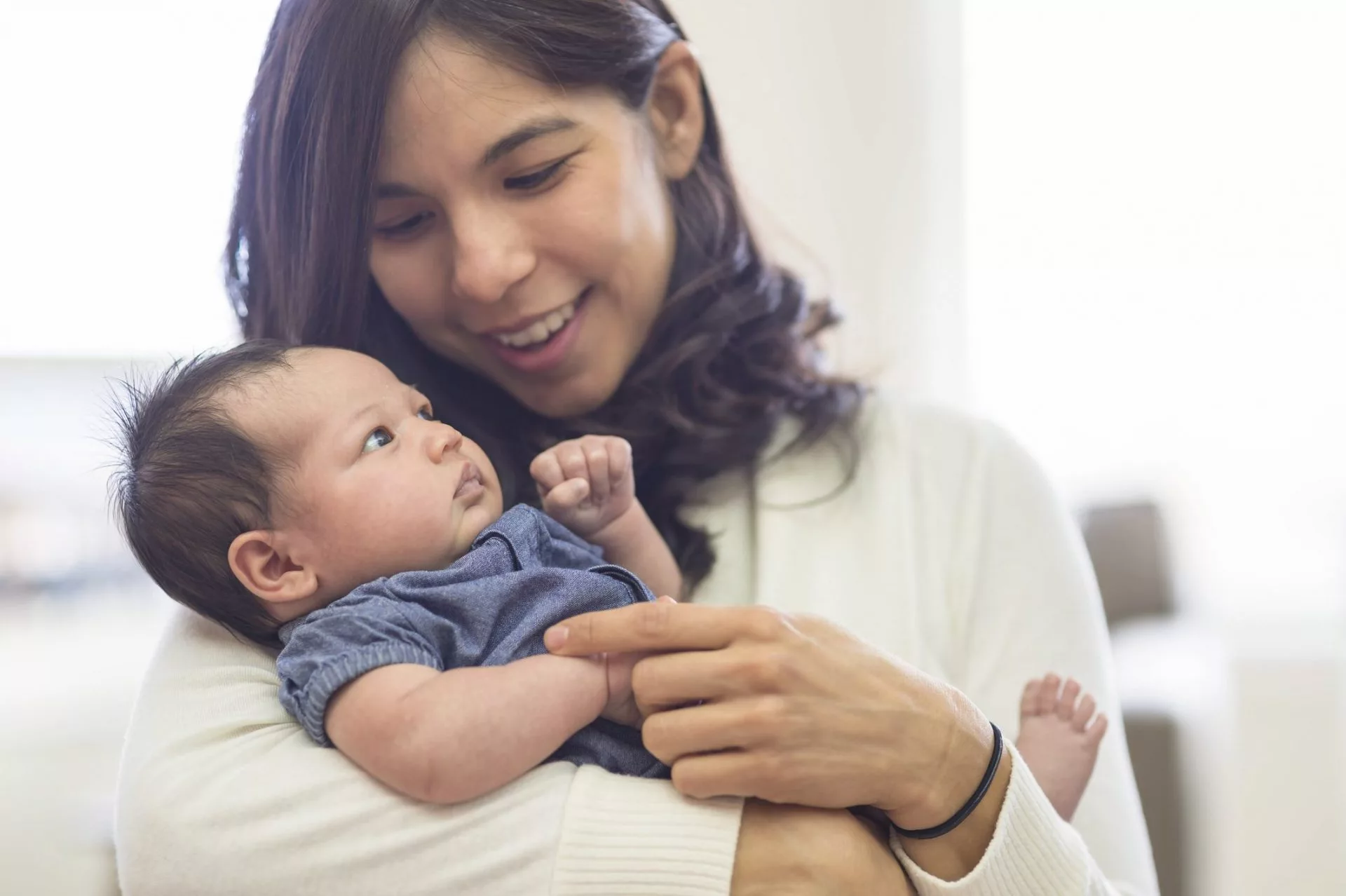 Close up of a mother holding her newborn daughter. The mother is smiling and looking down at the baby.