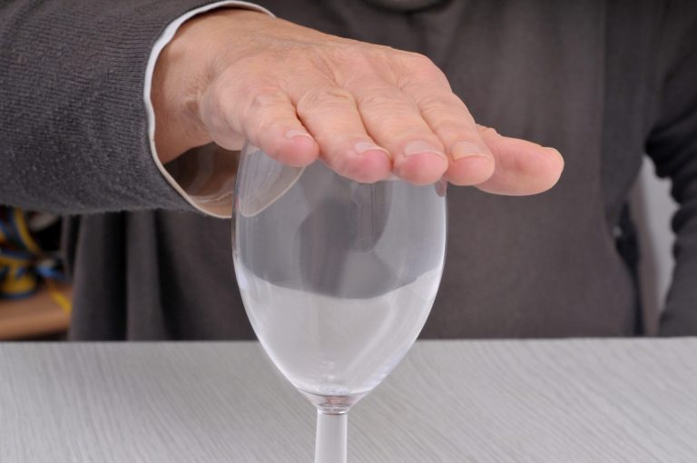 Dry January concept with hand resting on empty glass closeup