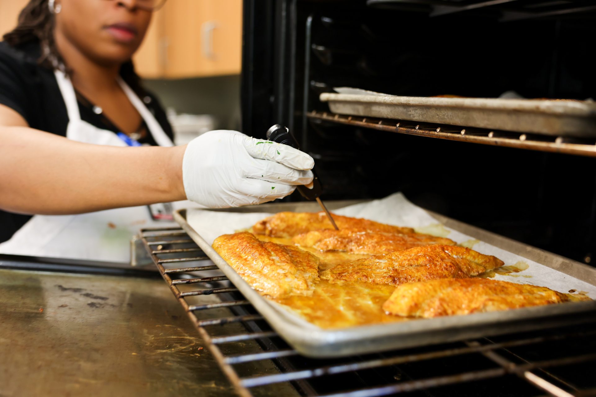 Chef is temp checking fish in the oven