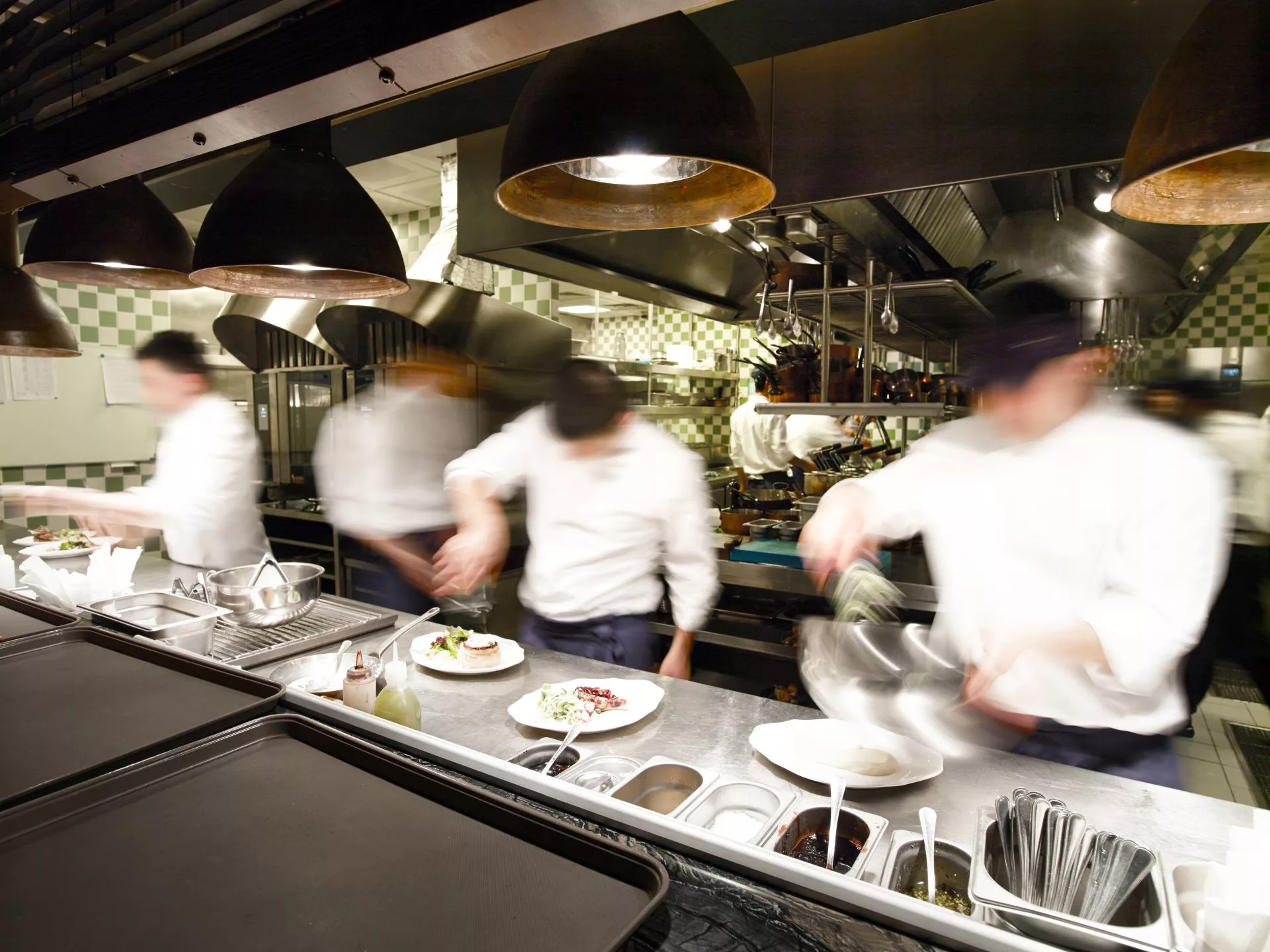 multiple chefs in a restaurant kitchen food prepping dinner
