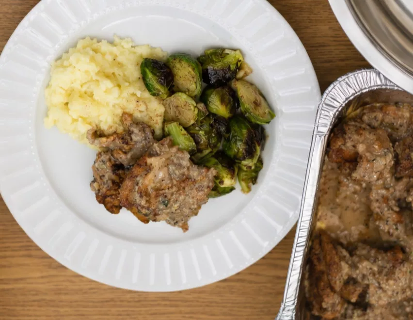 Plate of smothered chicken with mashed cauliflower and green vegetable