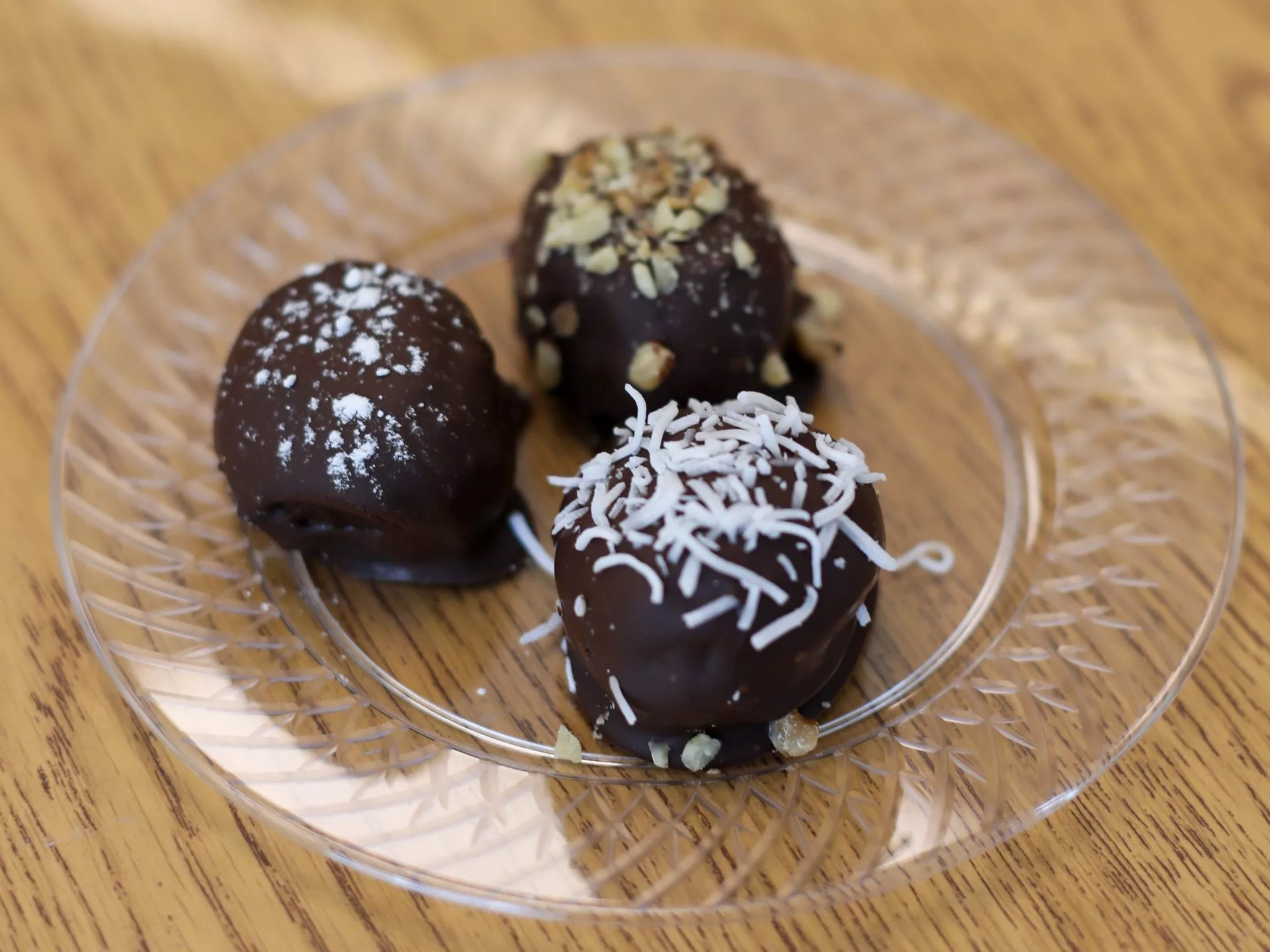 Three dark chocolate energy truffles with various toppings like nut, coconut or sugar