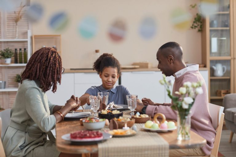 Photo of family of 3 sitting down at table to eat dinner