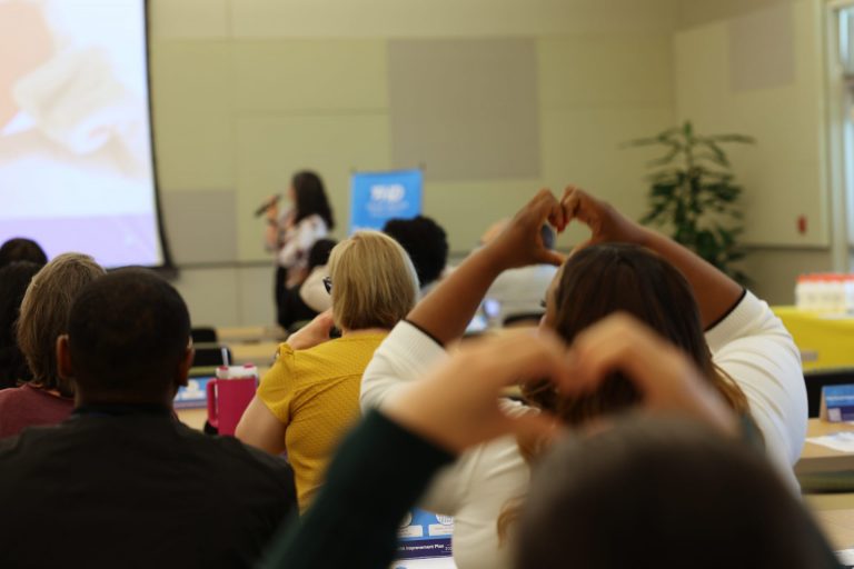 Room listening to presenter and lifting hands up in a heart gesture