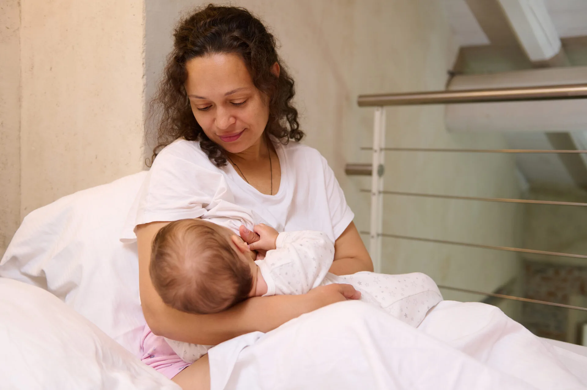 Mom sitting in bed breastfeeding her baby