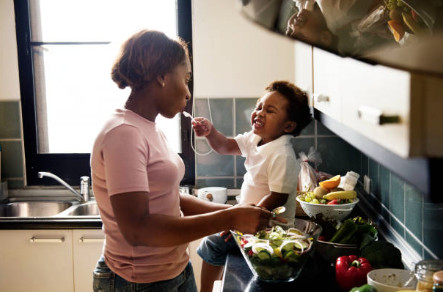 kid feeding mother with cooking food in the kitchen