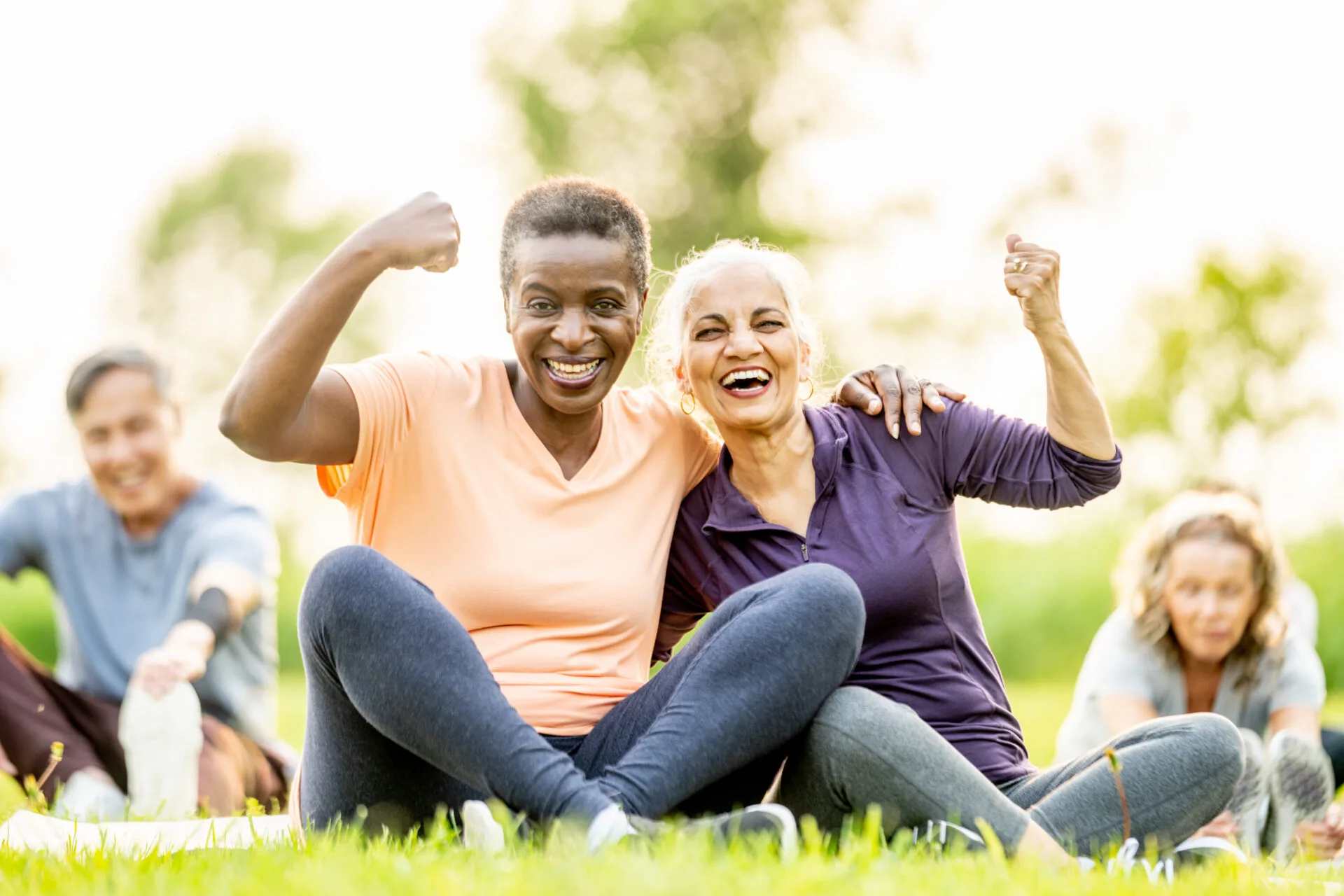 Two elderly ladies sitting on the grass smiling.